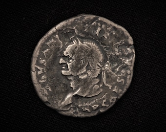 Könnte beinhalten: Eine silberne Münze mit dem Profil einer Person, die einen Helm trägt. Die Münze hat einen erhöhten Rand und ist vom Alter abgenutzt.