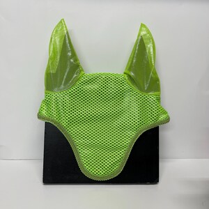 May include: A bright green horse fly bonnet with mesh ears and a decorative trim. The bonnet is designed to protect a horse's head from insects.
