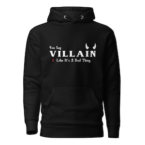 A black You Say Villain Like Its A Bad Thing hoodie with cute devil horns created by graphic apparel company Midnight Gypsy Designs as part of their Dark Academia clothing and Bookish Merch clothing line.