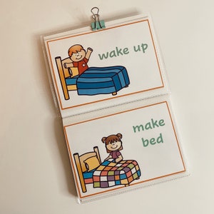 May include: Two illustrated cards showing a child making a bed and a child waking up. The cards are in a clear plastic sleeve with a binder clip.