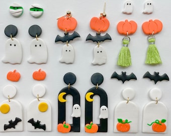 Könnte beinhalten: Eine Sammlung von Ohrringen zum Thema Halloween. Designs umfassen Geister, Kürbisse, Fledermäuse und Mumien in verschiedenen Stilen. Die Ohrringe sind aus Polymer Clay gefertigt und weisen schwarze, weiße, orange und grüne Farben auf. Einige Ohrringe haben goldfarbene Akzente.