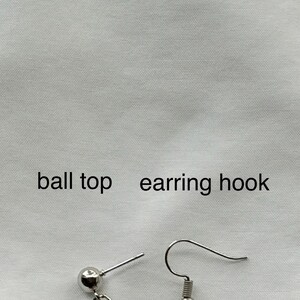 May include: Close-up of silver-colored earrings with a ball top and earring hook. The earrings have a geometric design. The text "ball top earring hook" is printed above the earrings.