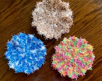 May include: Three crocheted dishcloths in different colors. One is brown, one is blue and white, and one is a mix of pink, green, orange, and yellow.