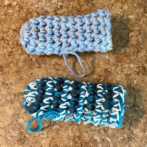 May include: Two crocheted dishcloths, one in blue and white and the other in blue and gray. Both dishcloths have a loop for hanging.