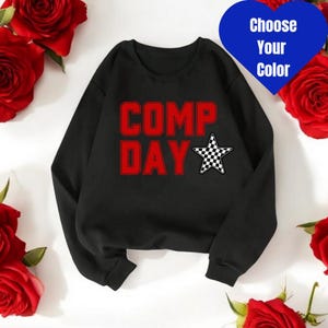 May include: Black sweatshirt with the words "COMP DAY" in red and a checkered star.