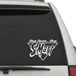 May include: A white vinyl decal with a black triangle and the text "Shop Smart... Shop S-Mart" on a black car window.