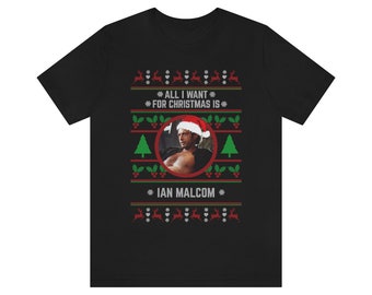 May include: Black t-shirt with a Christmas-themed design featuring a man wearing a Santa hat and the text "All I want for Christmas is Ian Malcolm".