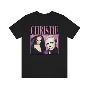 Puede incluir: Camiseta negra con un gráfico rosa y blanco de una mujer con el pelo rubio corto y el texto "Christie" en letras rosas.