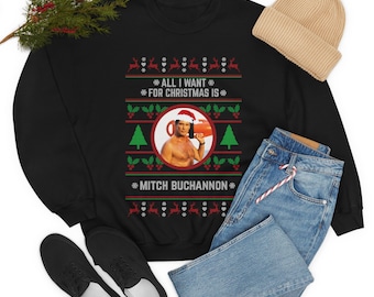 May include: Black Christmas jumper with a red and green pattern. The jumper features a picture of Mitch Buchannon from Baywatch wearing a Santa hat and holding a lifeguard buoy. The text "All I want for Christmas is Mitch Buchannon" is printed on the jumper.
