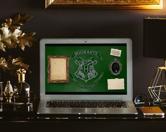 May include: A silver laptop computer with a green screen displaying the Hogwarts crest and the text "Hogwarts School of Witchcraft and Wizardry." The laptop is on a dark surface with a gold picture frame, a gold lamp, and a gold and black decorative object.