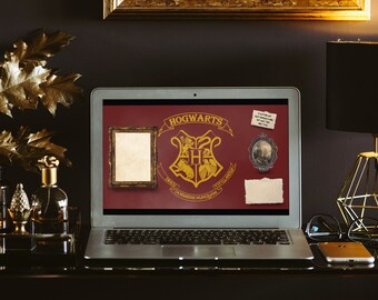 May include: A laptop computer with a red background displaying the Hogwarts crest and the words "Hogwarts School of Witchcraft and Wizardry". The laptop is on a dark surface with a gold picture frame, a small piece of paper, and a gold lamp.