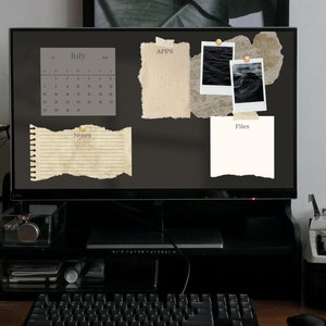 May include: A computer monitor displays a digital desktop organizer with a July calendar, polaroid-style photos, and paper notes. The screen is mounted on a black stand, with a keyboard and desk accessories in the foreground.