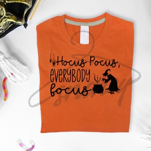 May include: Orange t-shirt with a black graphic that says "Hocus Pocus, Everybody Focus" with a witch stirring a cauldron.