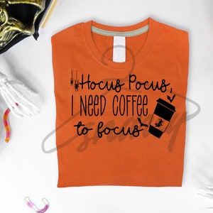 May include: Orange t-shirt with black text that reads "Hocus Pocus, I need coffee to focus" and a black silhouette of a coffee cup with a witch flying on a broomstick inside.