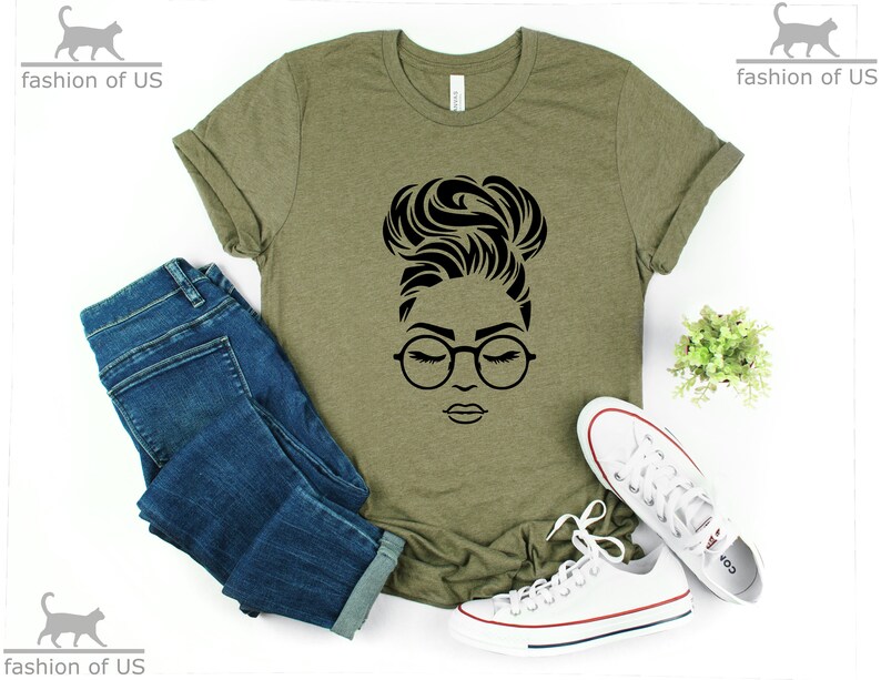 Peut inclure: Un t-shirt vert avec un motif noir repr&eacute;sentant une femme avec les cheveux en chignon et portant des lunettes. La femme regarde vers le bas, les yeux ferm&eacute;s.