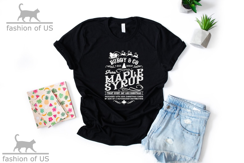 May include: Black t-shirt with a white graphic design that says "Bubby & Co. Est. 2021 Pure Maple Syrup Treat Every Day Like Christmas Packaged with Holiday Cheer by Son of a Nutcracker Distributing".