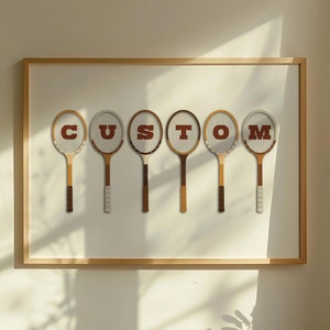 May include: A framed print with the word "CUSTOM" spelled out using six vintage tennis rackets. Each racket has a different letter of the word on the face.
