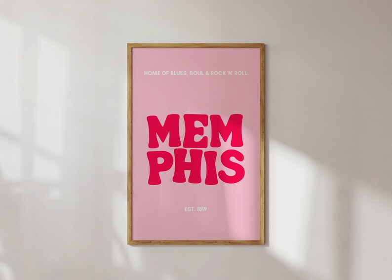 May include: A pink framed poster with the text "HOME OF BLUES, SOUL & ROCK 'N ROLL" at the top and "MEMPHIS" in large, pink, stylized letters in the center. The text "EST. 1819" is at the bottom of the poster.