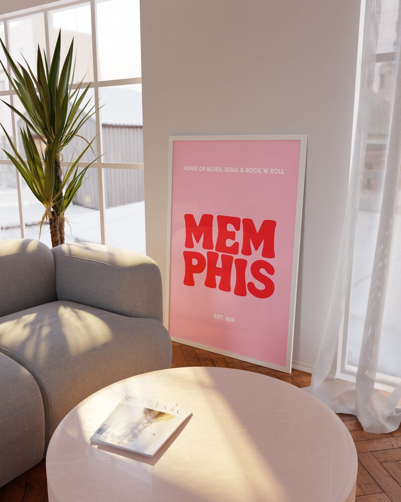 May include: Pink and white framed poster with the text "HOME OF BLUES, SOUL & ROCK 'N' ROLL" and "MEMPHIS" in red letters with "EST. 1819" below.