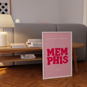 May include: Pink and white framed print with the text "HOME OF BLUES, SOUL & ROCK 'N ROLL" and "MEMPHIS" in large pink letters. The text "EST. 1819" is below the word "MEMPHIS".