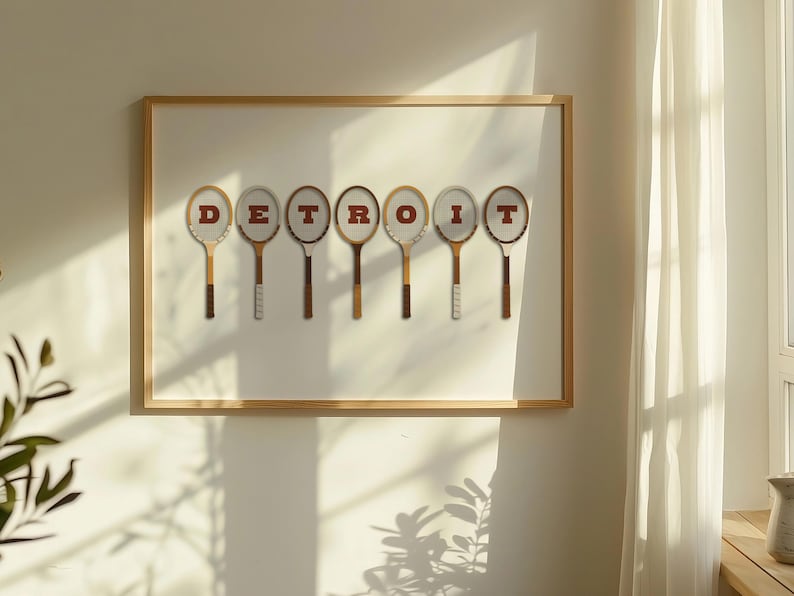 May include: A framed print with the word 'DETROIT' spelled out using vintage tennis rackets. The rackets are brown and white with red lettering.