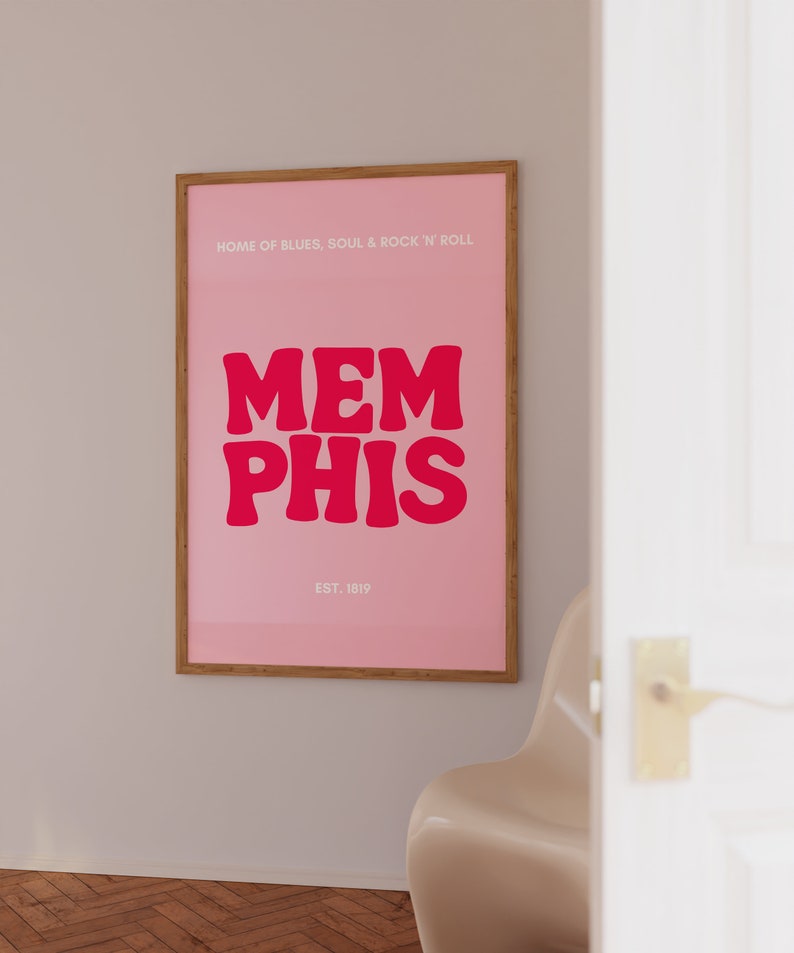 May include: A pink poster with a wooden frame featuring the text "HOME OF BLUES, SOUL & ROCK 'N' ROLL" and the word "MEMPHIS" in large, bold, red letters. The text "EST. 1819" is printed below the word "MEMPHIS".