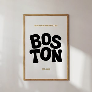 以下が含まれることがあります： 大きな黒い文字で「BOSTON」と書かれた額入りのアートプリント。その上には「BOSTON NEVER GETS OLD」というフレーズが金色の文字で、下には「EST. 1630」と書かれています。フレームは明るい茶色です。