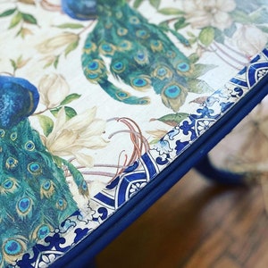 Pode incluir: Uma mesa com tampo de design azul e branco com um design de pav&atilde;o. O tampo da mesa &eacute; pintado de azul ao redor das bordas.