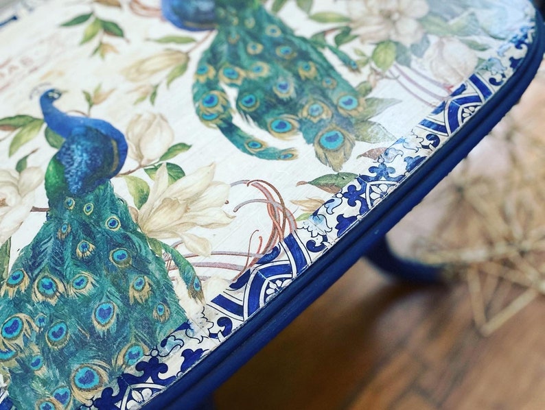 Pode incluir: Uma mesa com tampo de design azul e branco com um design de pav&atilde;o. O tampo da mesa &eacute; pintado de azul ao redor das bordas.