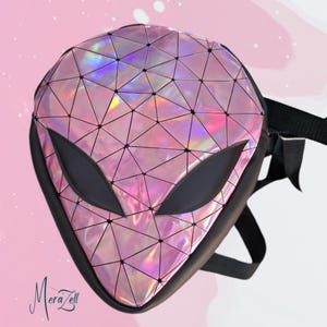 May include: Pink and black alien-shaped backpack with a geometric pattern. The backpack has a holographic, iridescent finish and black accents. The straps are black.