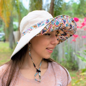 Wide Brim Sun Hat, Gardening Hat for Women, Chin Strap Hat, Floral Hat Ladies, Reversible Packable Summer Colorful Panama Hat A white sun hat with a paisley patterned underside. The hat has a wide brim and a chin strap.