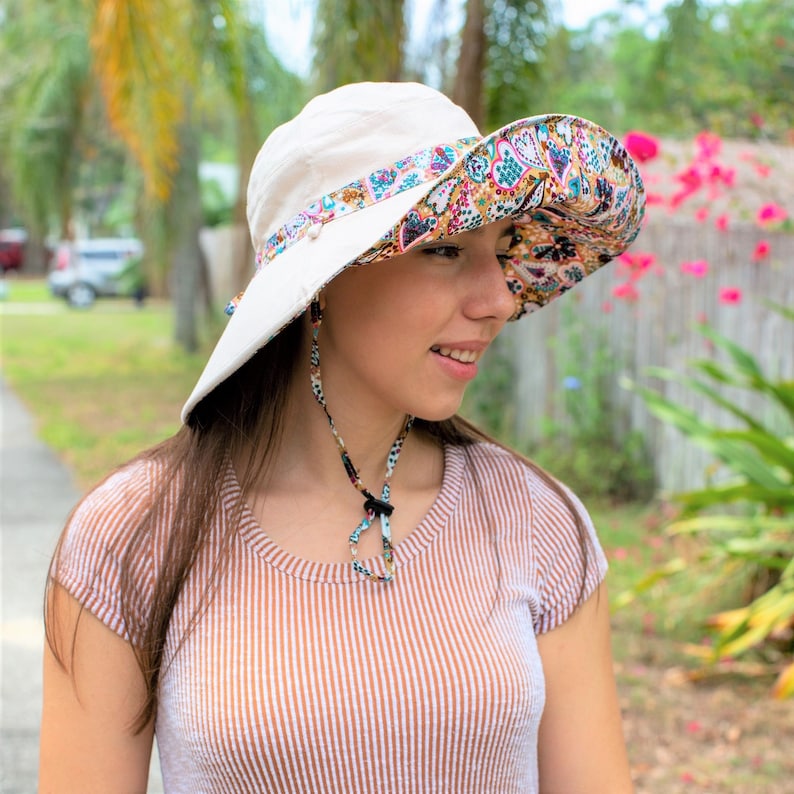 Wide Brim Sun Hat, Gardening Hat for Women, Chin Strap Hat, Floral Hat Ladies, Reversible Packable Summer Colorful Panama Hat A white sun hat with a paisley patterned underside. The hat has a wide brim and a chin strap.