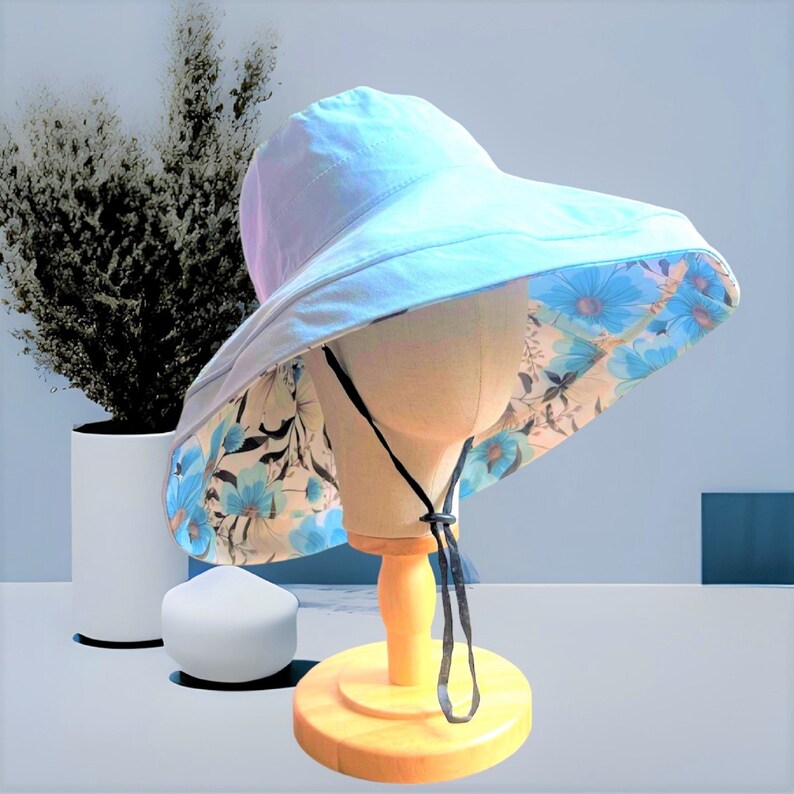 May include: A light blue sun hat with a floral print lining. The hat has a wide brim and a chin strap.