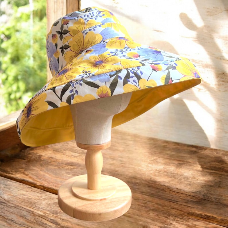 May include: A wide-brimmed sun hat with a yellow and blue floral print. The hat is made of fabric and has a wide brim that provides shade from the sun.