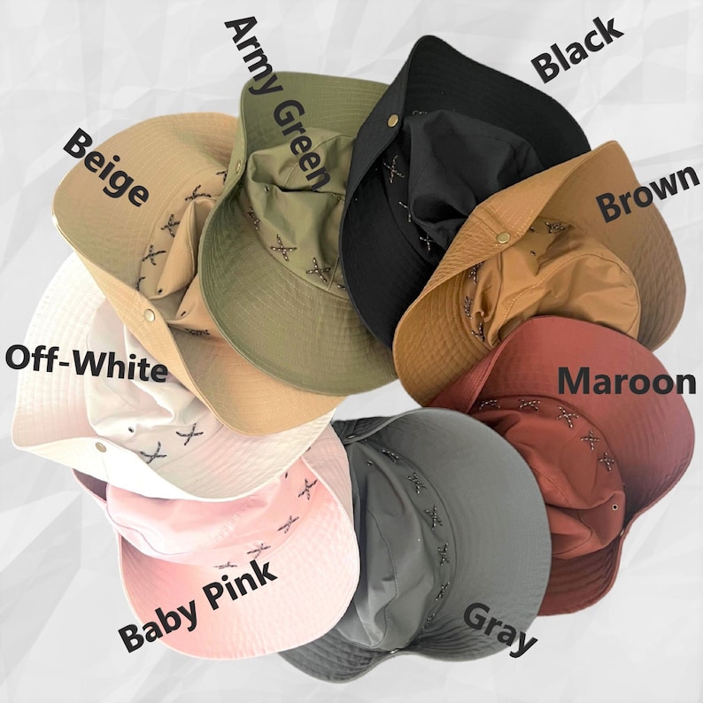 K&ouml;nnte beinhalten: Eine Sammlung von acht Fischerh&uuml;ten, die kreisf&ouml;rmig angeordnet sind und die Farben Beige, Army Green, Black, Brown, Maroon, Gray, Baby Pink und Off-White aufweisen. Jeder Hut verf&uuml;gt &uuml;ber einen metallischen Druckknopf und dekorative Kreuzstiche.