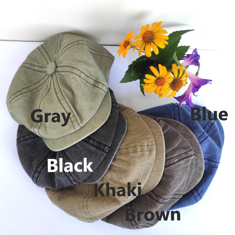 Peut inclure: Plusieurs casquettes de style gavroche de couleurs vari&eacute;es : gris, noir, kaki, marron et bleu. Chaque casquette pr&eacute;sente une couronne arrondie et une courte visi&egrave;re rigide. Les mots "Gray", "Black", "Khaki", "Brown" et "Blue" sont &eacute;crits sur chaque casquette. Des fleurs jaunes et violettes sont en arri&egrave;re-plan.