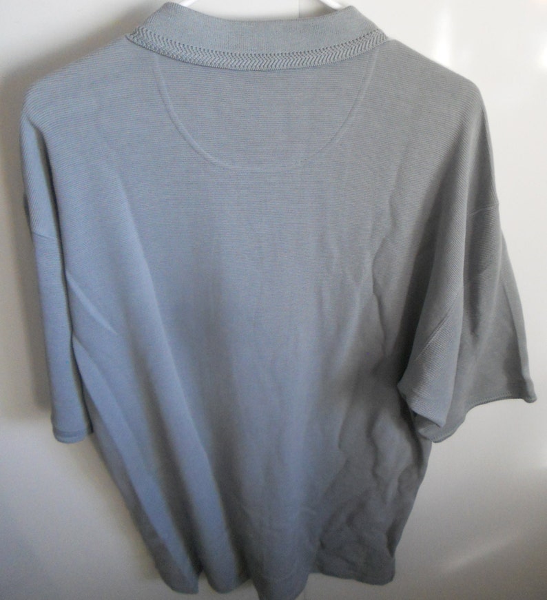 May include: A gray short-sleeved polo shirt with a ribbed texture.