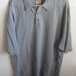 May include: A light gray short-sleeved polo shirt with a button-up collar and a Tommy Bahama logo on the left chest.
