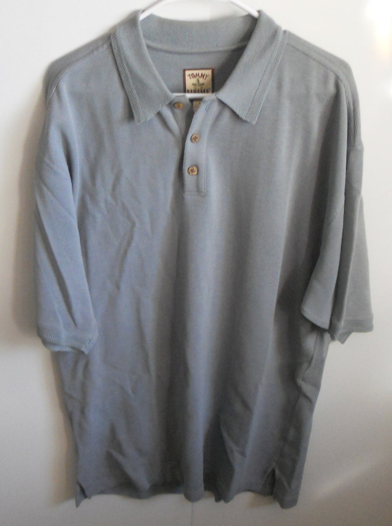 May include: A light gray short-sleeved polo shirt with a button-up collar and a Tommy Bahama logo on the left chest.