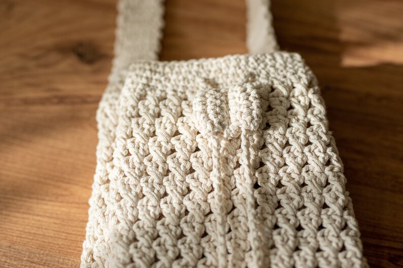 Peut inclure: Un sac en crochet blanc avec une anse nou&eacute;e. Le sac est fait d'un fil &eacute;pais et textur&eacute; et a un design simple et minimaliste.