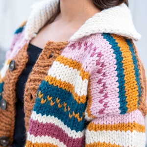 May include: A colorful striped cardigan with a white collar. The cardigan is knitted with a variety of colors, including brown, pink, white, yellow, and blue.