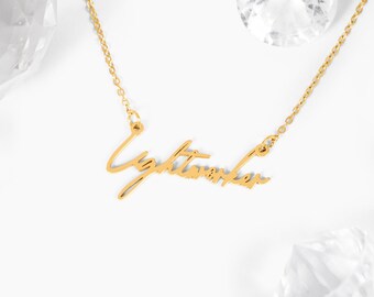 Puede incluir: Collar de oro con un colgante de escritura cursiva que dice "Lightworker".