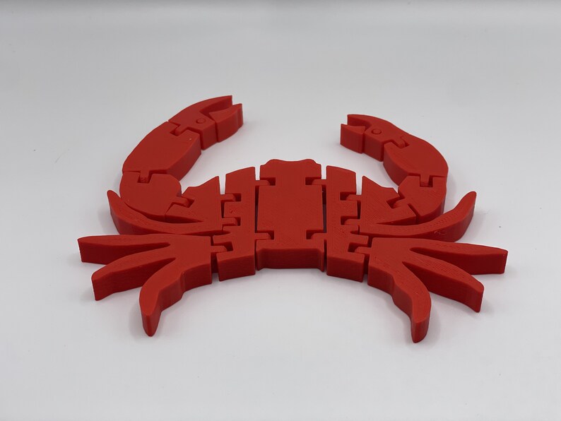 May include: A red plastic crab toy with segmented legs and claws. The crab is made of multiple pieces that fit together.