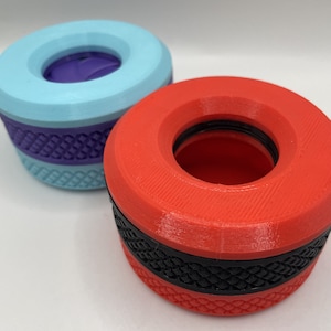 May include: Two 3D printed bottle stoppers, one is red with a black band and the other is light blue with a purple band.