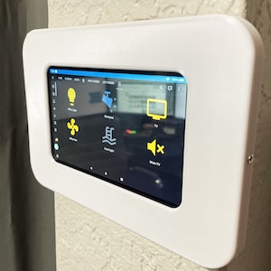 Peut inclure: Une tablette murale blanche avec un écran noir affichant un panneau de commande de maison intelligente. Le panneau comporte des icônes pour les lumières, les ventilateurs, les lumières de la piscine et la télévision. Le texte "Mute TV" est affiché à l'écran.