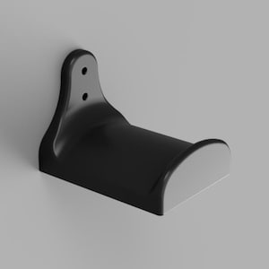 May include: A black plastic wall mount with two holes for screws. The mount has a curved shape to hold a round object.