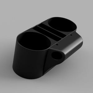 Op de afbeelding: Een zwarte organizer met twee ronde bekerhouders en een verdeeld bovenstuk voor kleine items. Het ontwerp bevat een zijhandvat en een kleine ronde opening. De organizer is gemaakt van een solide, matte materiaal.