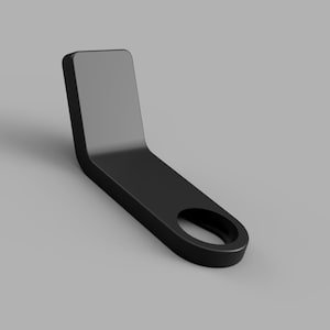 May include: A matte black, L-shaped bracket featuring a flat, rectangular vertical section and a horizontal base with a circular cutout at the end. The object has smooth, rounded edges and a solid, uniform construction throughout its entire form.