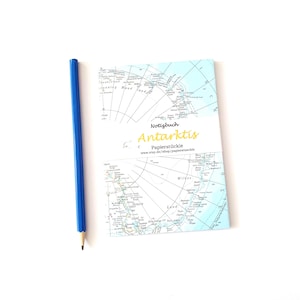 Könnte beinhalten: Ein blauer Bleistift neben einem Notizbuch mit einer Karte der Antarktis. Das Notizbuch hat das Wort "Antarktis" in gelber Schrift und die Wörter "Notizbuch" und "Papierstuckle" in schwarzer Schrift.