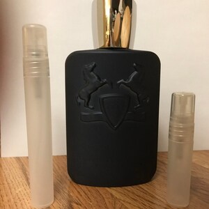 May include: A black bottle of perfume with a silver cap and two small clear travel-sized bottles of perfume.